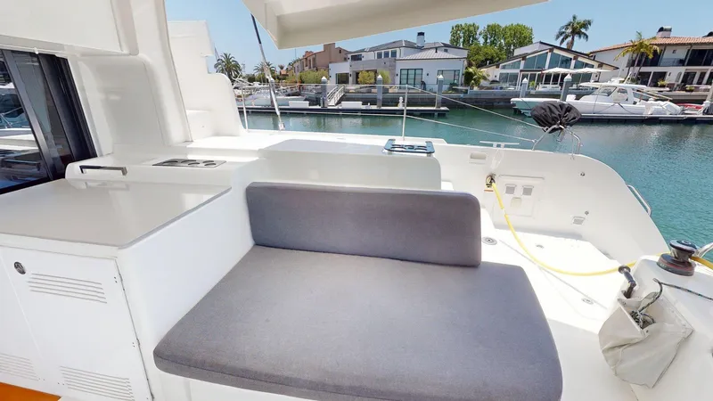 Sliver Fern Yacht Photos Pics 2020 Lagoon 46 yacht deck with seating, docked in a marina with waterfront homes.