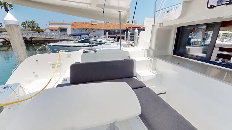 Sliver Fern Yacht Photos Pics Spacious deck of 2020 Lagoon 46 catamaran docked at marina, featuring comfortable seating.