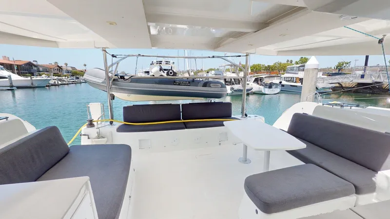 Sliver Fern Yacht Photos Pics Spacious deck of 2020 Lagoon 46 catamaran with seating and table, docked at marina.