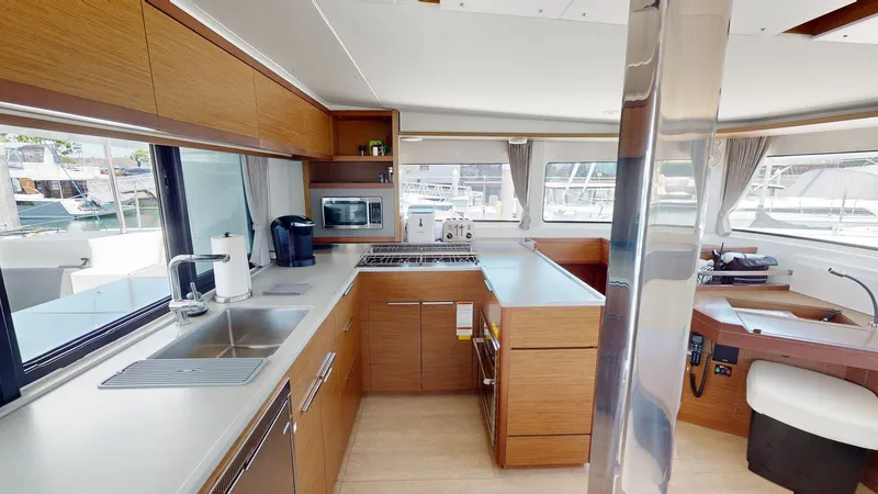 Sliver Fern Yacht Photos Pics Modern kitchen interior of 2020 Lagoon 46 yacht with wood cabinetry and stainless steel appliances.