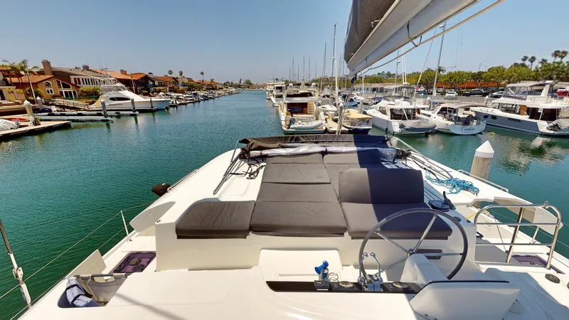 Sliver Fern Yacht Photos Pics 2020 Lagoon 46 catamaran docked in a marina, featuring spacious deck and steering wheel.