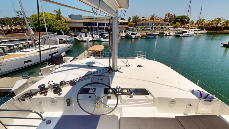Sliver Fern Yacht Photos Pics 2020 Lagoon 46 catamaran docked in a marina, featuring a spacious helm and serene water view.