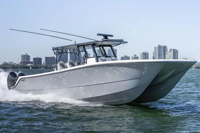  Yacht Photos Pics 2022 Invincible 40 Cat boat cruising on water with city skyline in background.