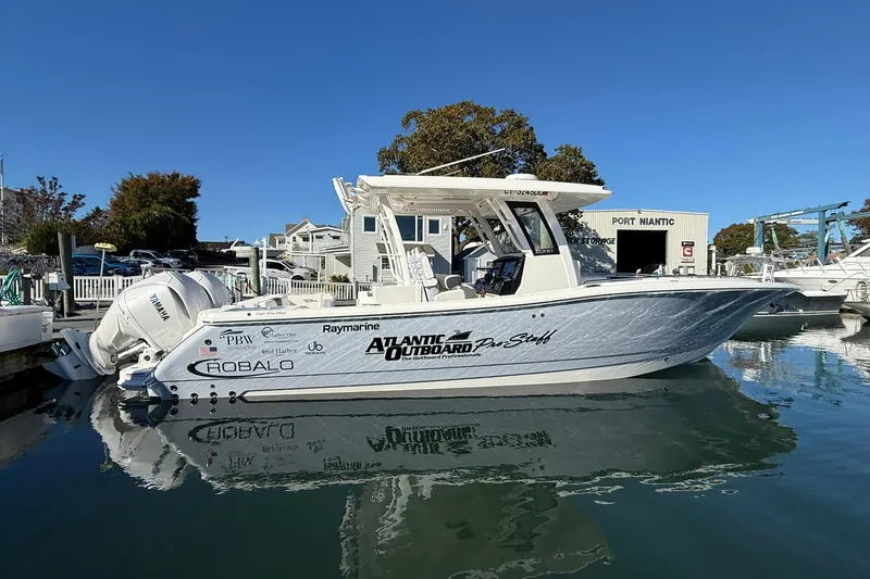  Yacht Photos Pics 2025 Robalo R300 Center Console boat docked at marina under clear blue sky.