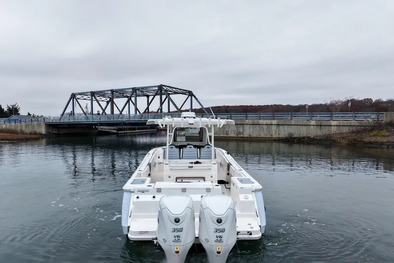  Yacht Photos Pics 2025 Robalo R300 Center Console boat near a bridge on a cloudy day.