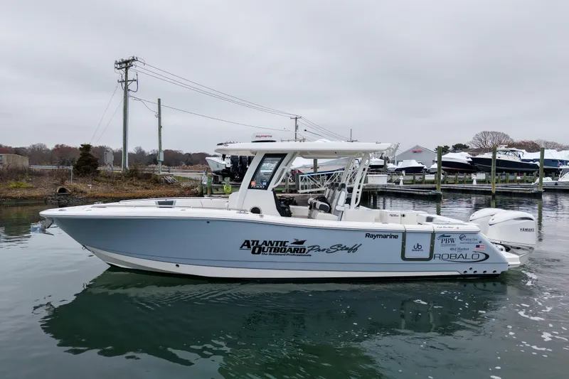  Yacht Photos Pics 2025 Robalo R300 Center Console boat docked in a marina, featuring sleek design and branding.