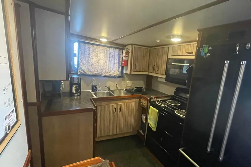  Yacht Photos Pics 1973 Custom 58&rsquo; Steel Marco Seiner kitchen with modern appliances and wooden cabinetry.