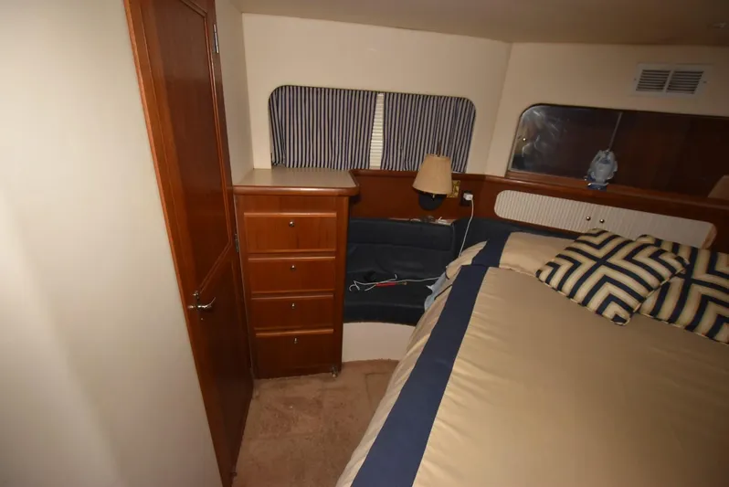 Miss Dot Yacht Photos Pics 1997 Carver 405 Aft Cabin Motoryacht bedroom with striped pillows and wooden cabinetry.