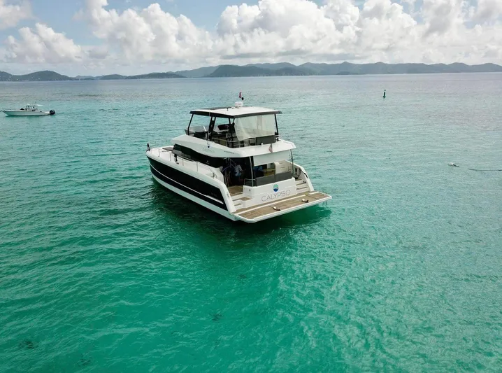 Calypso Yacht Photos Pics 2021 Fountaine Pajot MY6 yacht on turquoise water with scenic mountain backdrop.