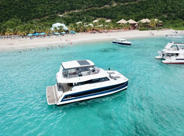 Calypso Yacht Photos Pics 2021 Fountaine Pajot MY6 yacht in turquoise waters near a tropical beach.