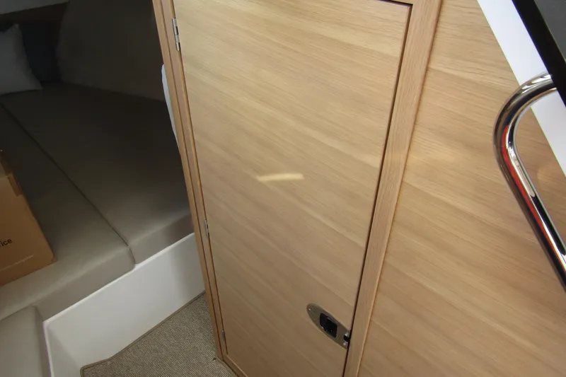  Yacht Photos Pics Interior cabin of 2025 Nimbus Weekender 9, featuring wooden door and cozy sleeping area.