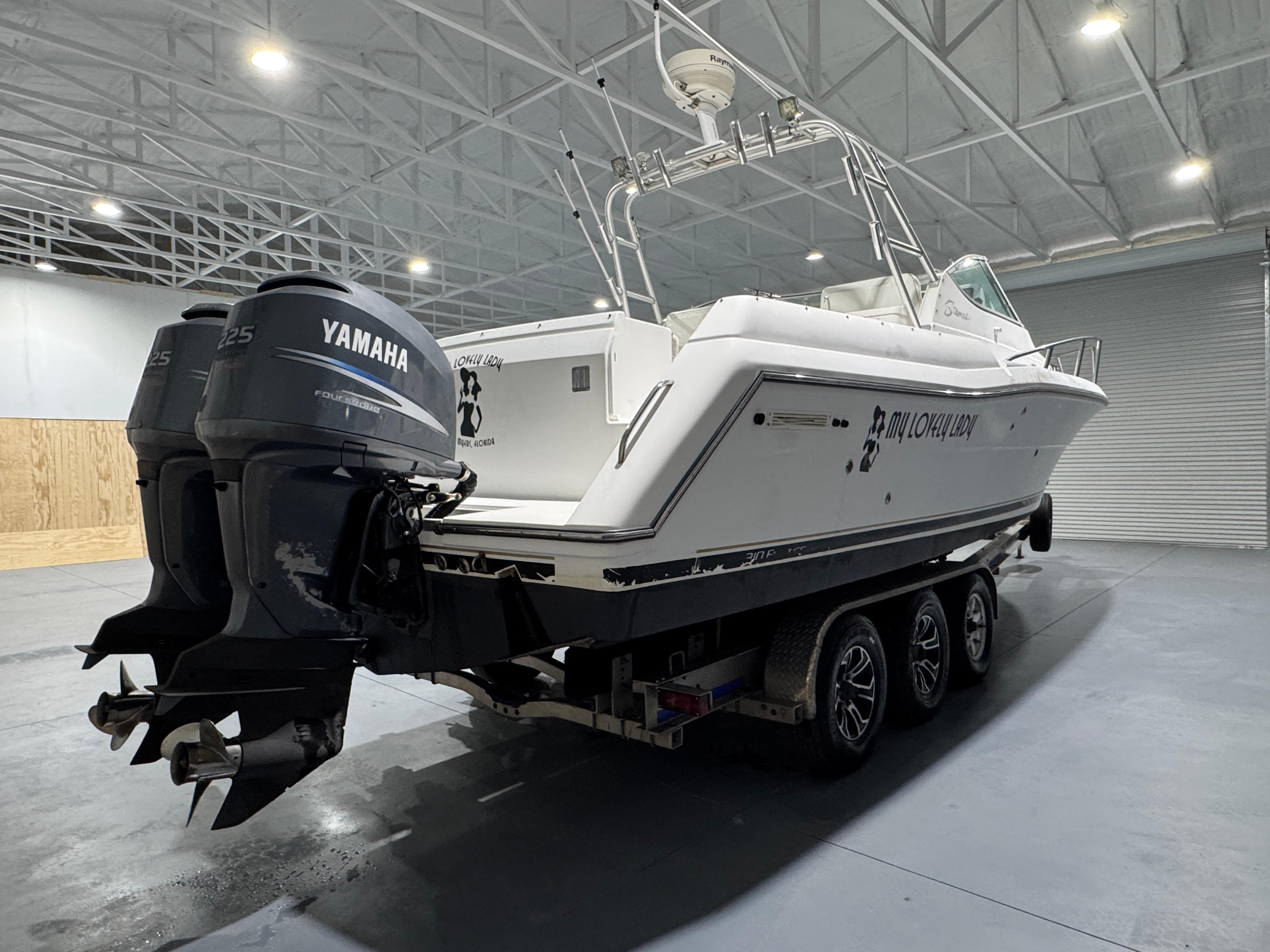 2005 Stamas 310 Express boat with Yamaha engines on a trailer in a warehouse.