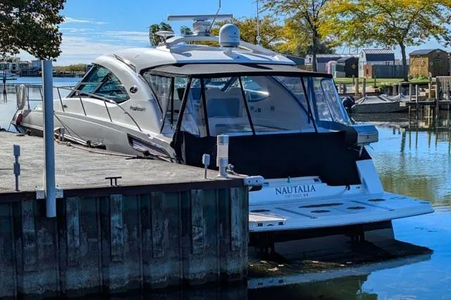 Nautalia Yacht Photos Pics 2013 Sea Ray 470 Sundancer yacht docked at a marina, surrounded by calm water and trees.