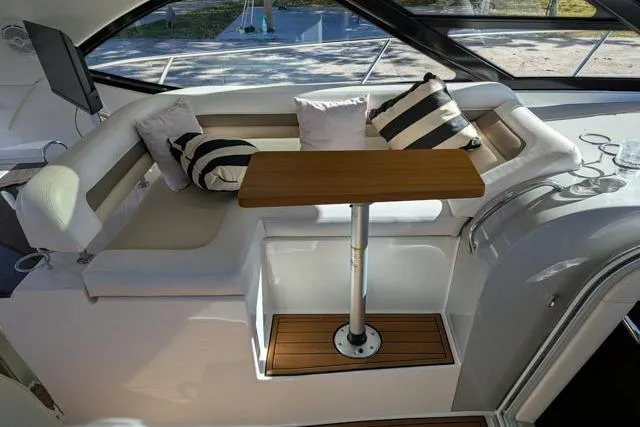 Nautalia Yacht Photos Pics Luxurious seating area on 2013 Sea Ray 470 Sundancer yacht with striped cushions and wooden table.