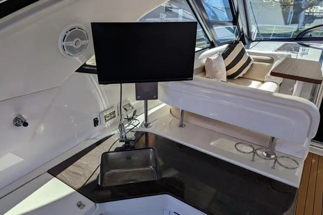 Nautalia Yacht Photos Pics Interior of 2013 Sea Ray 470 Sundancer yacht with sink, TV, and seating area.