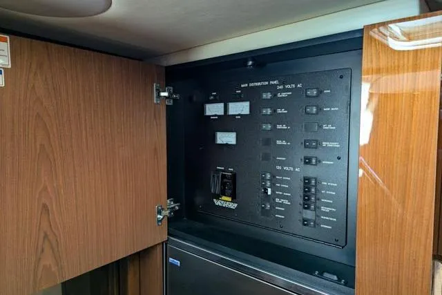 Nautalia Yacht Photos Pics Electrical panel inside 2013 Sea Ray 470 Sundancer yacht, featuring wooden cabinetry.