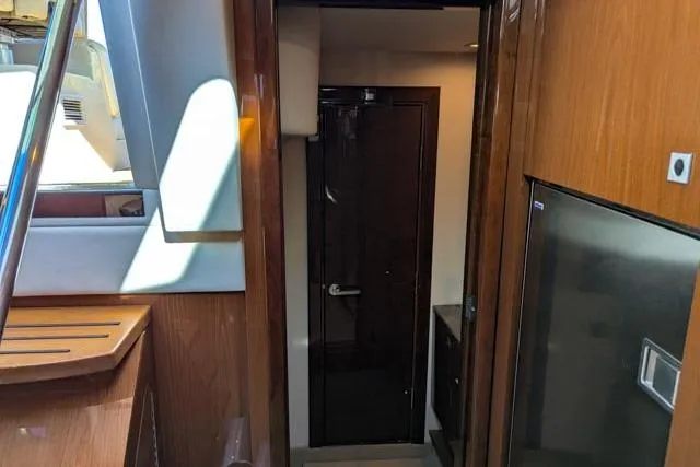 Nautalia Yacht Photos Pics Interior view of 2013 Sea Ray 470 Sundancer yacht, featuring wooden cabinetry and a sleek door.