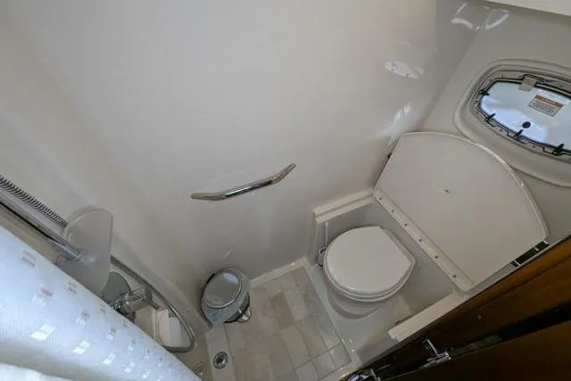 Nautalia Yacht Photos Pics Bathroom interior of 2013 Sea Ray 470 Sundancer yacht, featuring toilet and porthole window.