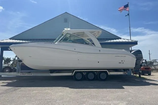  Yacht Photos Pics 2018 World Cat 320 DC boat on trailer, parked near a building with flags.