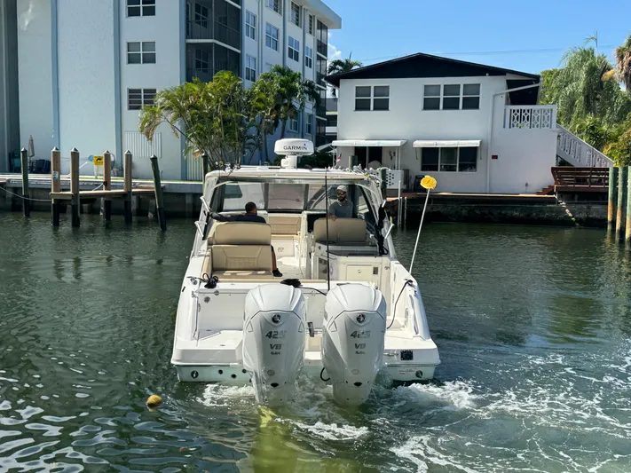  Yacht Photos Pics 2019 Everglades 340 Dual Console boat navigating a canal near residential buildings.