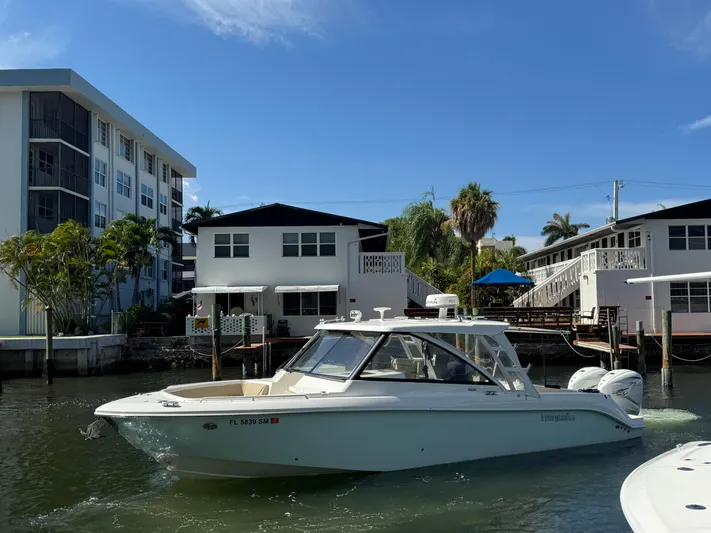  Yacht Photos Pics 2019 Everglades 340 Dual Console boat cruising near waterfront homes under a clear blue sky.
