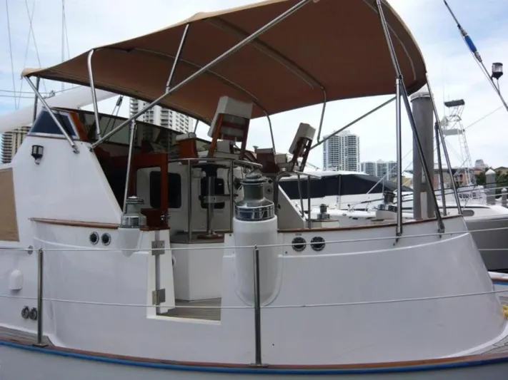 Maraya Yacht Photos Pics 1990 Cheoy Lee Sloop with canopy, docked in marina, city skyline in background.