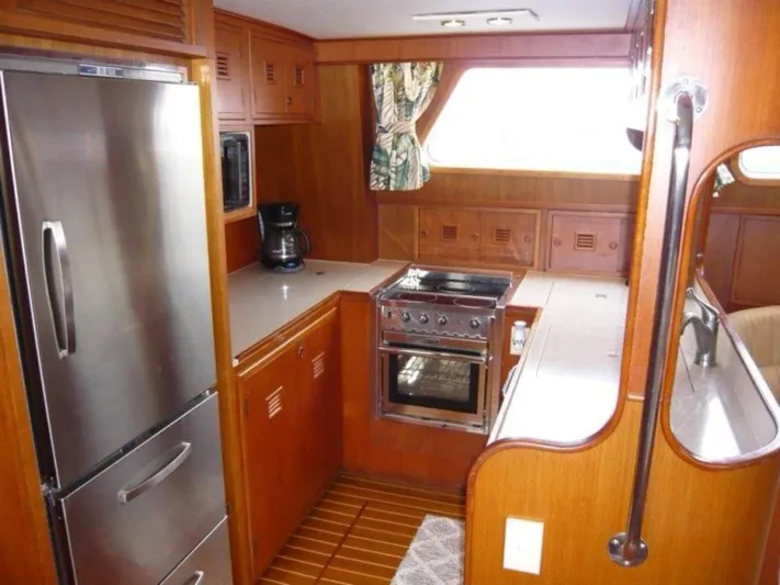 Maraya Yacht Photos Pics 1990 Cheoy Lee Sloop kitchen with wood cabinetry, stainless steel appliances, and compact design.