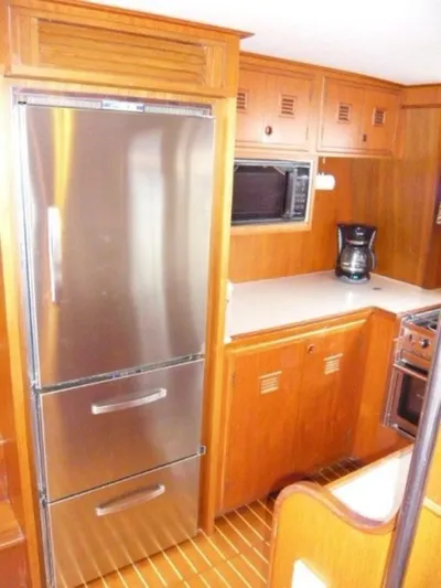 Maraya Yacht Photos Pics 1990 Cheoy Lee Sloop kitchen with stainless steel fridge, wooden cabinets, and modern appliances.