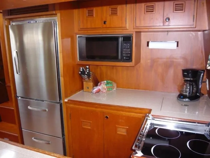 Maraya Yacht Photos Pics Galley kitchen in 1990 Cheoy Lee Sloop with stainless steel appliances and wooden cabinetry.