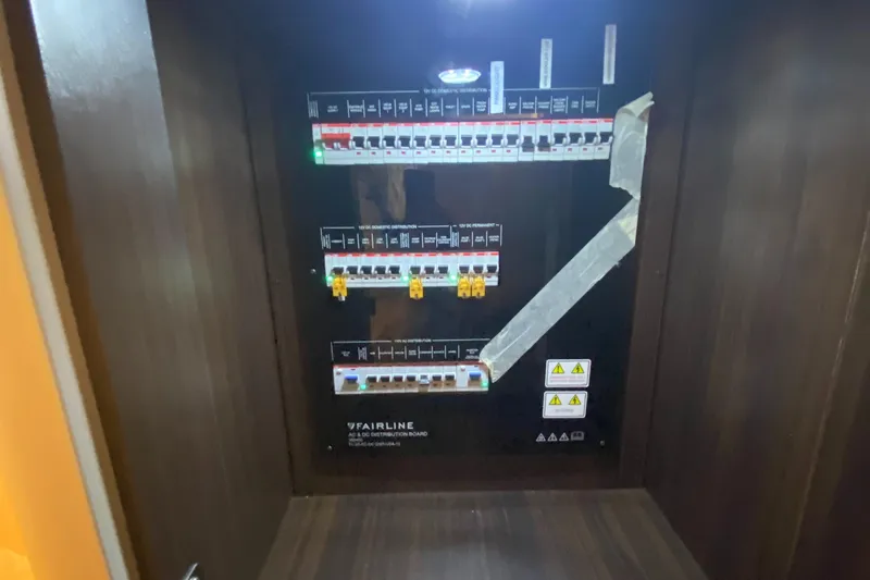 Just Us Yacht Photos Pics Electrical panel inside 2022 Fairline F//Line 33 yacht, featuring circuit breakers and warning labels.