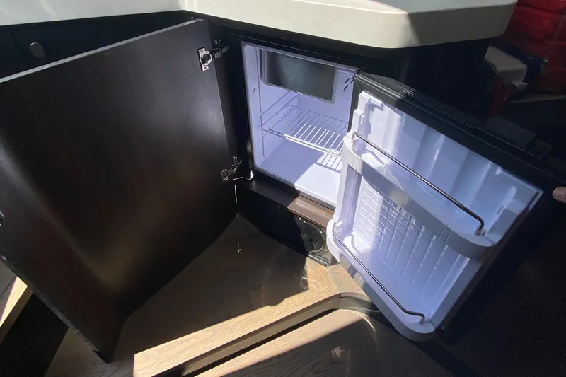 Just Us Yacht Photos Pics Open mini fridge inside 2022 Fairline F//Line 33 yacht, showcasing interior storage space.
