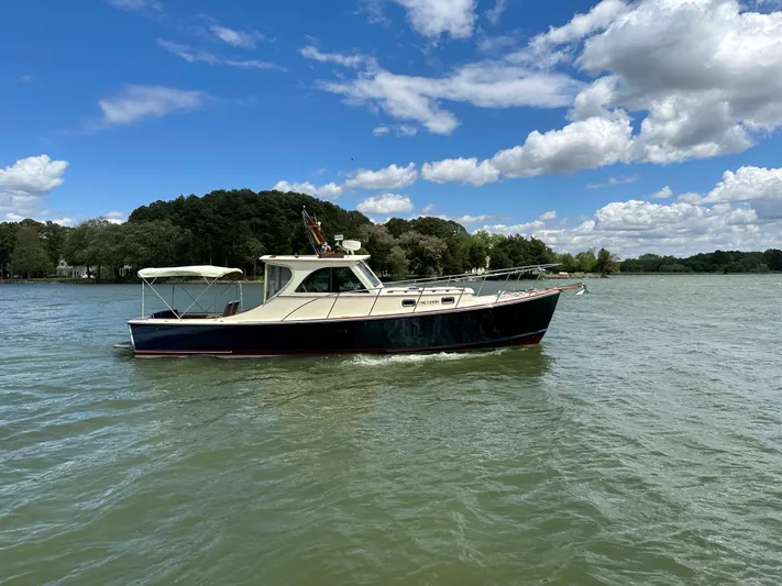  Yacht Photos Pics 2001 Mast & Mallet 38 Picnic Boat cruising on a serene lake under a blue sky.