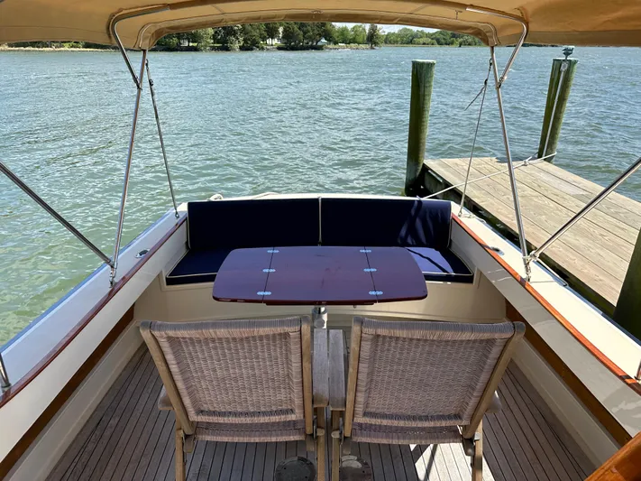 Yacht Photos Pics 2001 Mast & Mallet 38 Picnic Boat, docked with seating and table, on calm water.
