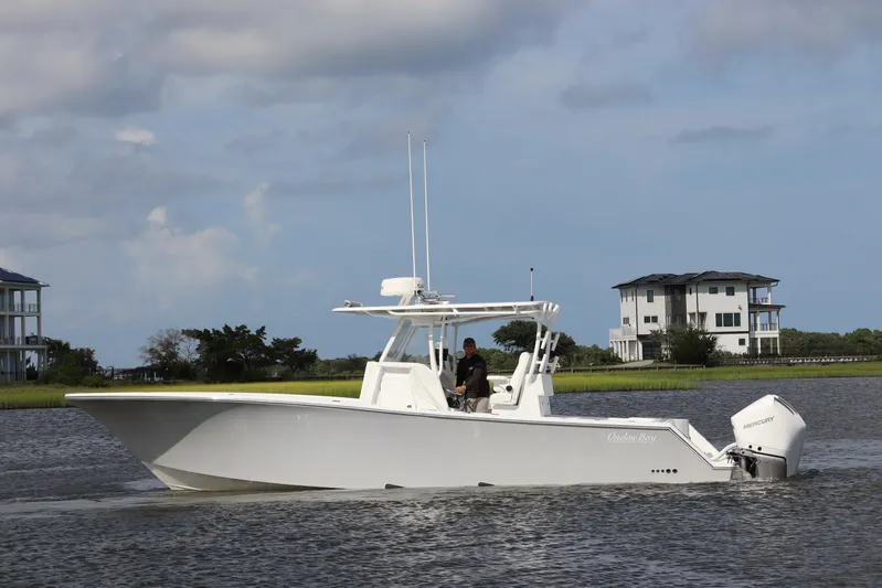  Yacht Photos Pics 2022 Onslow Bay 33 boat cruising on a calm waterway with houses in the background.