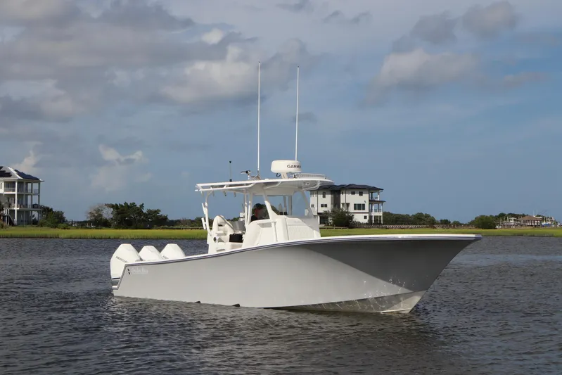  Yacht Photos Pics 2022 Onslow Bay 33 boat cruising on a calm waterway with houses in the background.