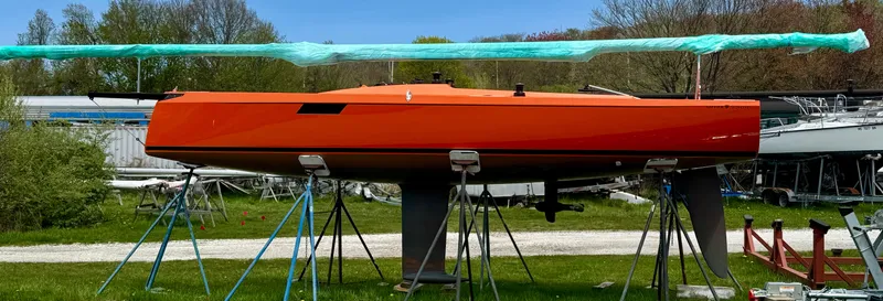  Yacht Photos Pics 2025 Saffier 24 Lite sailboat in vibrant orange on stands, surrounded by greenery.