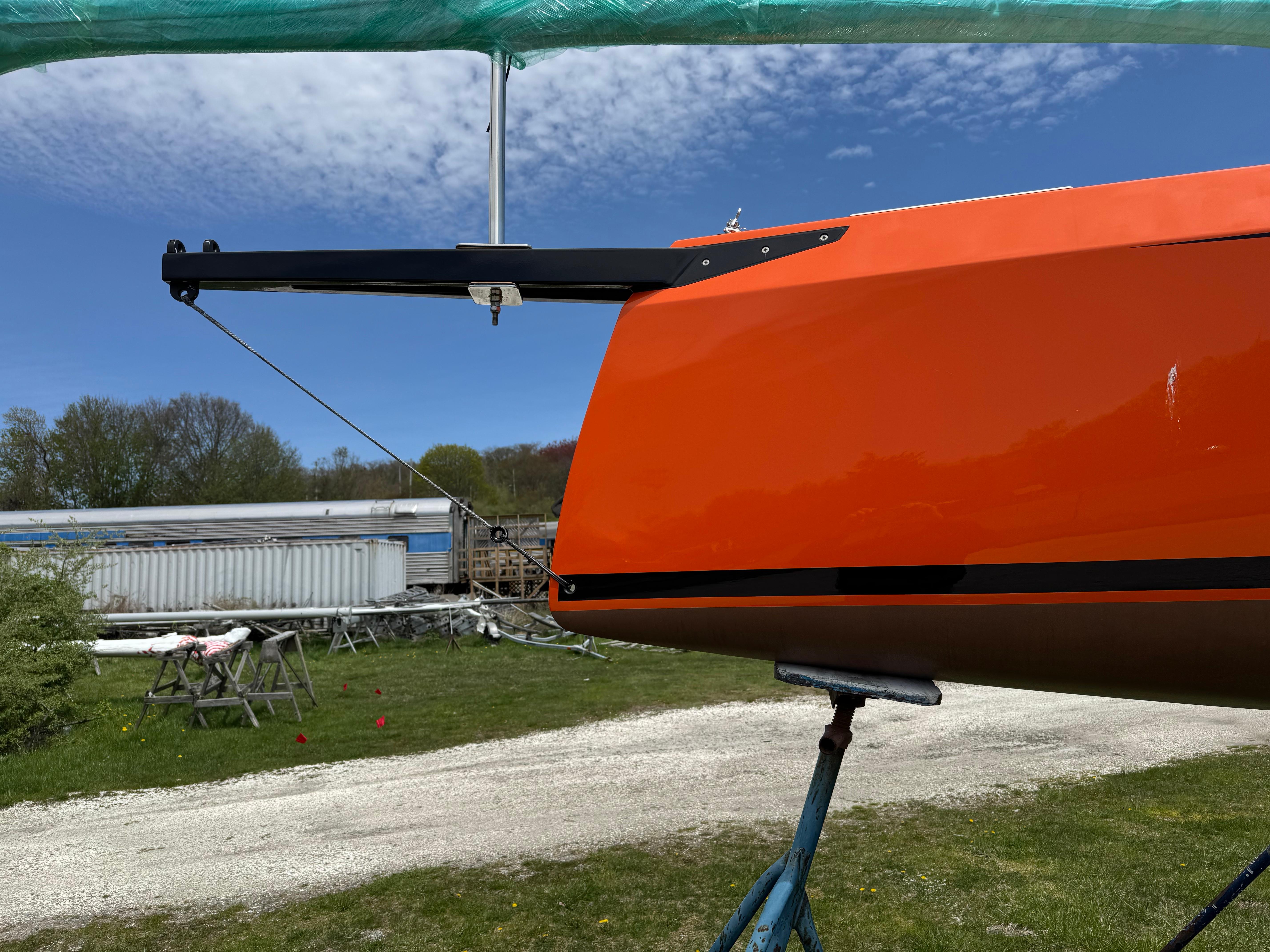 2025 Saffier 24 Lite sailboat with vibrant orange hull on a stand outdoors.