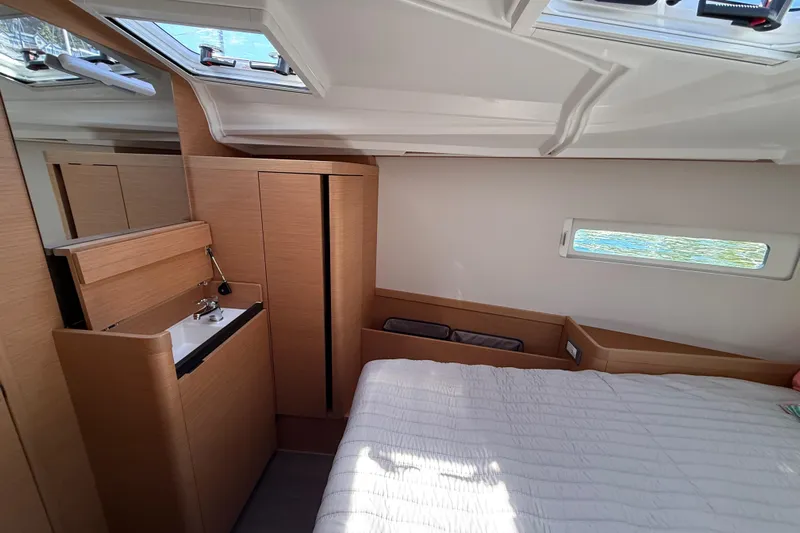 Lucky Dog Yacht Photos Pics Interior of 2023 Jeanneau Sun Odyssey 410 yacht cabin with bed and wooden cabinetry.