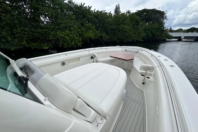  Yacht Photos Pics 2015 Boston Whaler 370 Outrage boat with spacious seating and table, docked near lush greenery.