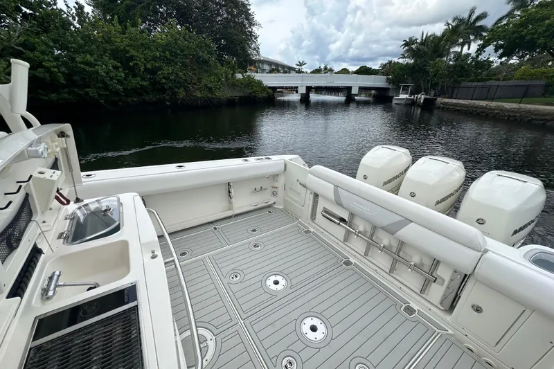  Yacht Photos Pics 2015 Boston Whaler 370 Outrage boat with triple Mercury engines, docked near a bridge.