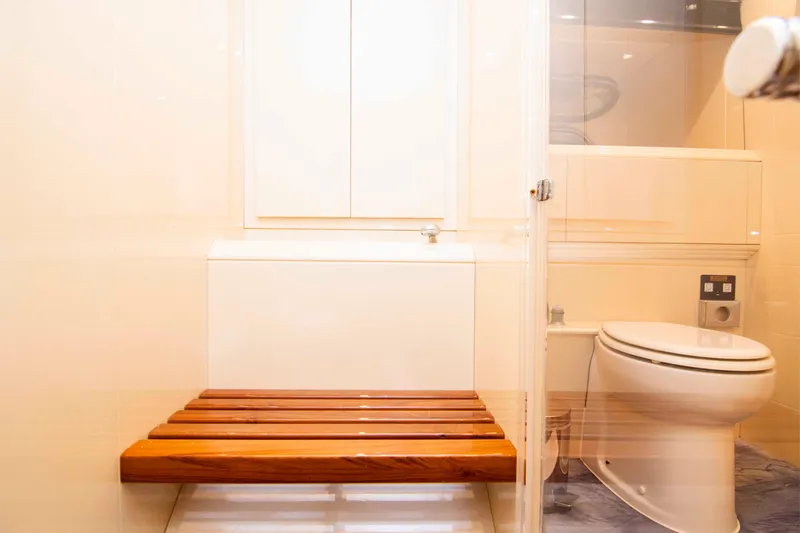  Yacht Photos Pics Luxurious bathroom interior on a 1999 Mangusta 105 yacht, featuring a wooden bench and modern toilet.