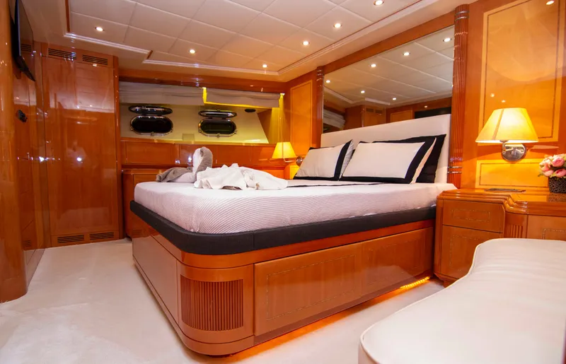  Yacht Photos Pics Luxurious bedroom interior of 1999 Mangusta 105 yacht with elegant wood paneling and ambient lighting.