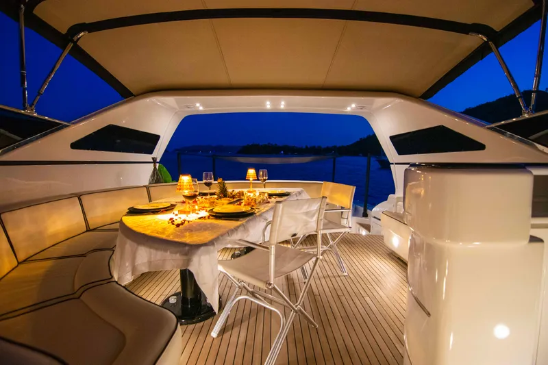  Yacht Photos Pics Luxurious 1999 Mangusta 105 yacht dining area with elegant table setting at sunset.