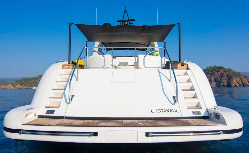  Yacht Photos Pics Luxury 1999 Mangusta 105 yacht docked, rear view with clear blue sky and water.