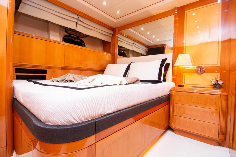  Yacht Photos Pics Luxurious bedroom interior on a 1999 Mangusta 105 yacht, featuring elegant wood finishes.