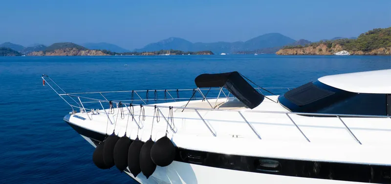  Yacht Photos Pics Luxury Mangusta 105 yacht from 1999 on serene blue waters with scenic island backdrop.