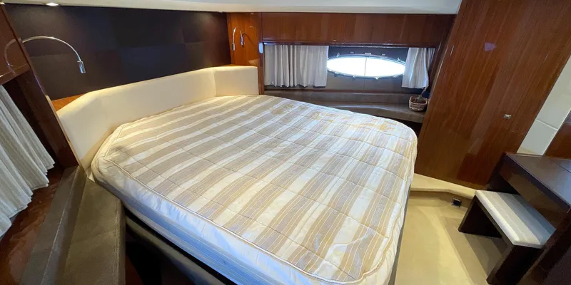  Yacht Photos Pics Luxurious bedroom interior of a 2012 Princess 72 yacht with a large bed and elegant wood paneling.