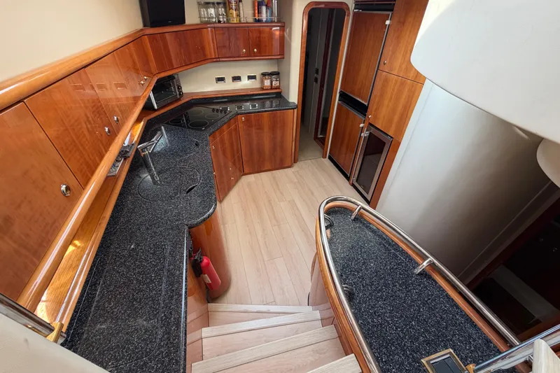 What Is Life Yacht Photos Pics Luxurious kitchen interior of 2000 Sunseeker Manhattan 62 yacht with wood cabinetry and granite countertops.
