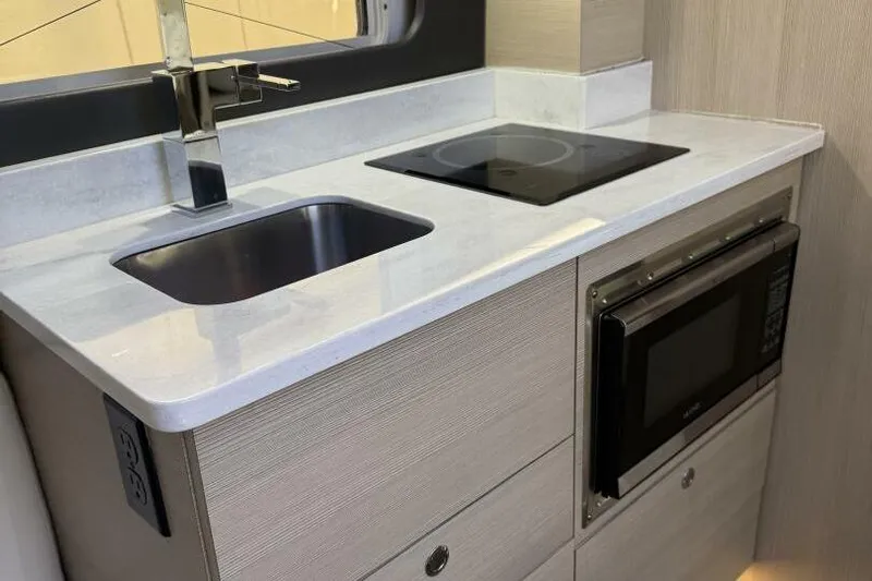  Yacht Photos Pics Modern kitchen area in 2022 Scout 425 LXF boat with sink, stove, and microwave.