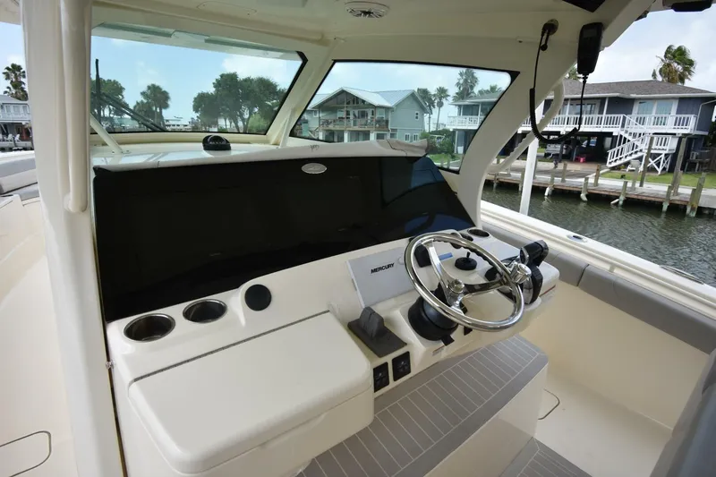  Yacht Photos Pics 2022 Scout 425 LXF boat helm with steering wheel and control panel, dockside view.